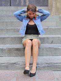 Full length of a young woman sitting on staircase