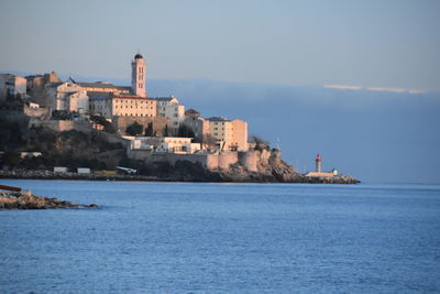 Sea by buildings against sky