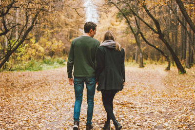 Rear view of couple walking in autumn forest