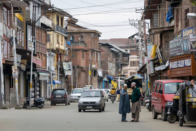 Rear view of vehicles on road along buildings