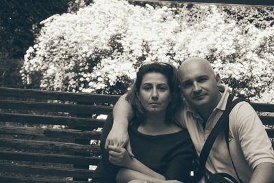 Portrait of couple sitting on bench at park