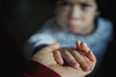 Boy holding hand of mother at home