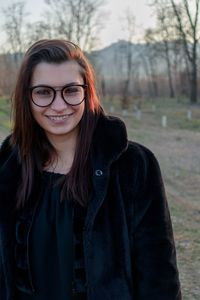 Portrait of smiling young woman standing in forest