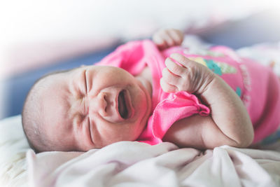 Baby girl crying while lying on bed