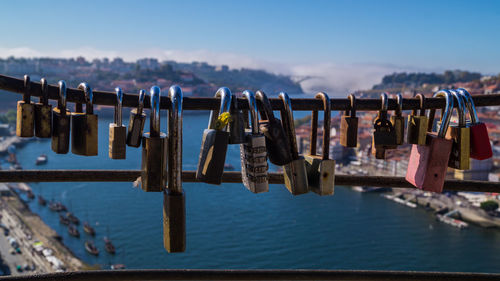 Close-up of padlocks hanging on railing against river