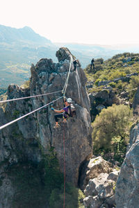 Concept: adventure. woman with helmet, harness and backpack. diving down a zip line in the wild nature. doing via ferrata in the mountains.