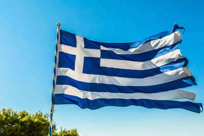 Low angle view of greek flag waving against clear blue sky