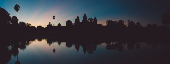 Silhouette trees by lake against sky during sunset