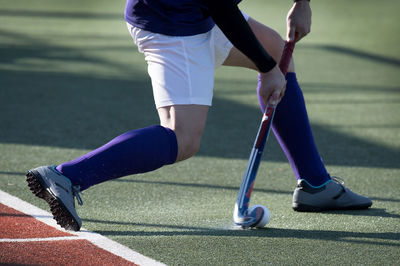 Low section of man playing hockey on field