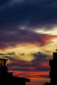 High section of silhouette built structures against scenic sky