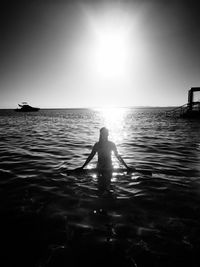 Silhouette person in sea against sky