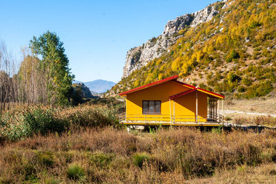 Built structure on field by mountain against sky