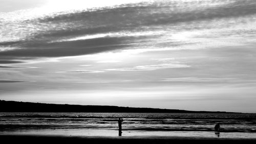 Silhouette people on beach against sky