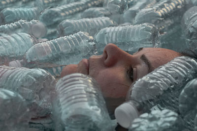 Close-up portrait of a woman surrounded by plastic bottles 