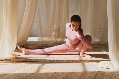 Young woman sitting on bed at home