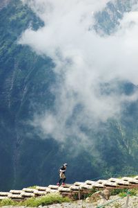 Man standing by tree on mountain against sky