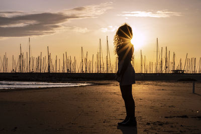 Woman standing at beach during sunset