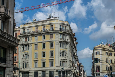 Summer low angle view of old apartment building in rome, italy. against blue sky with crane on top.