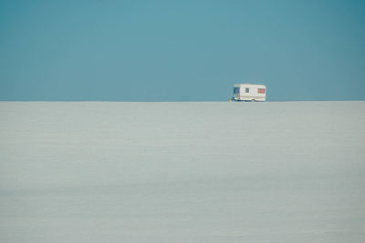 Lifeguard hut on sand against clear blue sky