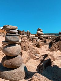 Stack of stones on rocks against clear blue sky