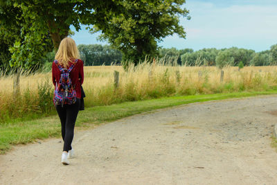 Full length of woman standing on grassland against trees