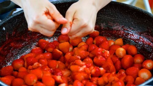 Cropped hands of woman crushing strawberries