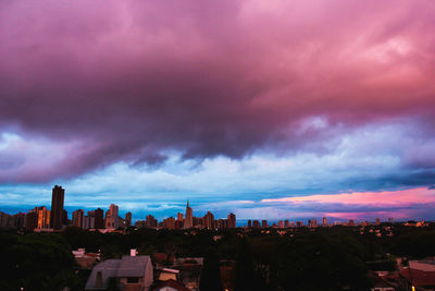 Buildings in city against dramatic sky