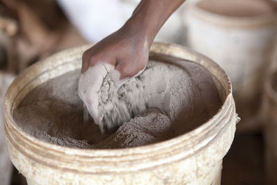 Close-up of hand in clay powder bucket