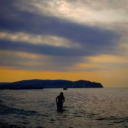 Silhouette man on beach against sky during sunset