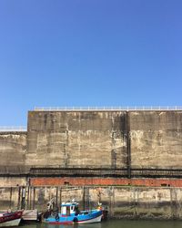 Built structure by river against clear blue sky