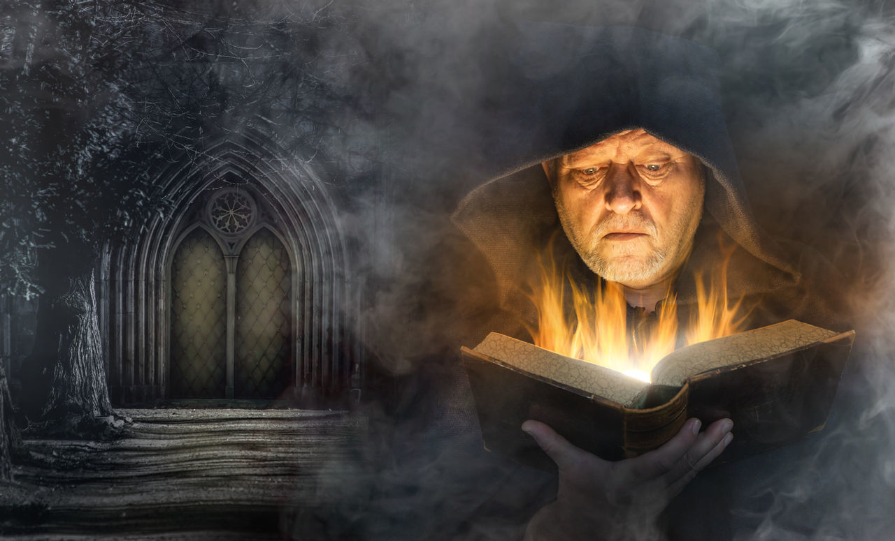 DIGITAL COMPOSITE IMAGE OF MAN READING BOOK WITH BURNING