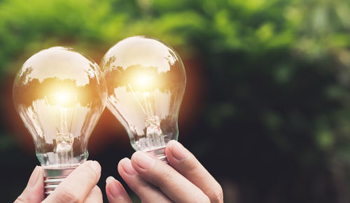 Cropped hands of person holding illuminated light bulbs