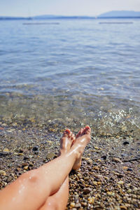 Female legs, a girl is sunbathing on pebble beach of geneva lake, summer vacations and travel