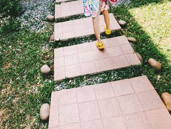 Low section of girl walking on tiles in park