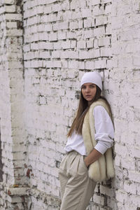 Full length of woman standing against brick wall