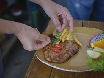 Chefs hand prepares a grilled pork ribs and decorates hearb