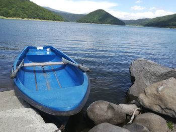 Boats moored on rock by lake