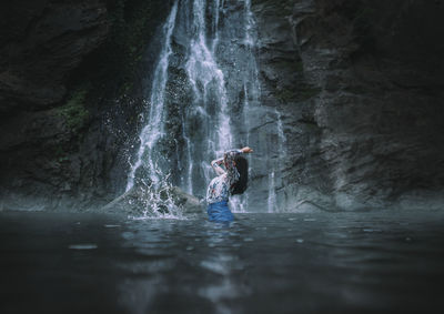 Woman standing in river against rock formation