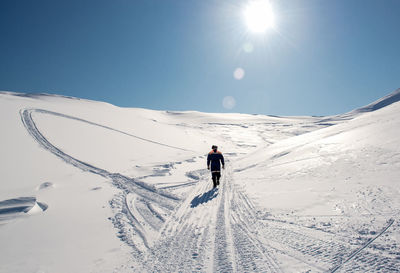 Rear view of person walking on snow covered pass amidst mountains against sky