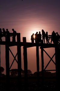 Low angle view of silhouette people on u bein bridge during sunset against sky