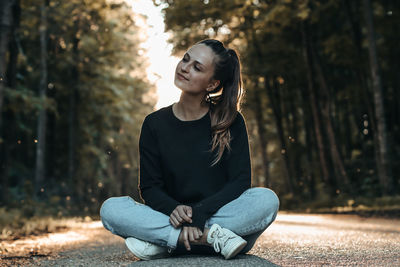 Young woman looking away while sitting on tree