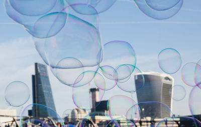 Close-up of buildings seen through bubbles in city against sky