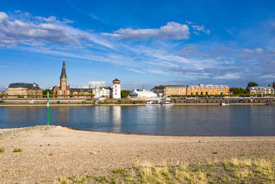 Buildings at waterfront against cloudy sky