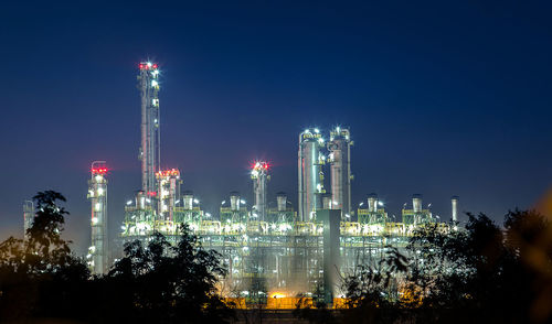 Low angle view of illuminated factory against sky at night