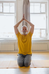 Man with gray hair meditates and does breathing exercises. sports fitness and physical exercises 