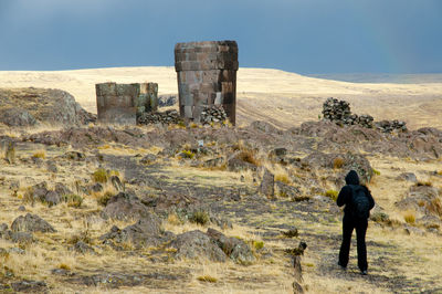 Rear view of men standing on field against sky