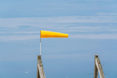 Side view of windsock blowing in wind against sky