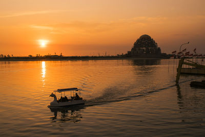 Silhouette boat in lake against sky during sunset