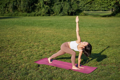 Full length of young woman exercising in park