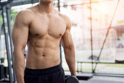 Midsection of shirtless man with arms raised